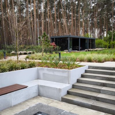 Minimalistyczne palenisko ogrodowe kontrastujące z naturalnymi nasadzeniami